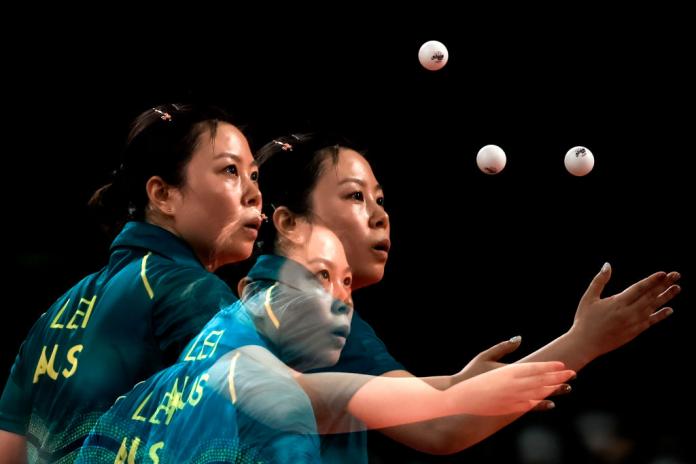 A female Para table tennis player serving the ball. The picture was taken with a multiple exposure in the camera.