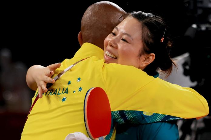 A female Para table tennis player hugs a man wearing a yellow Australian uniform