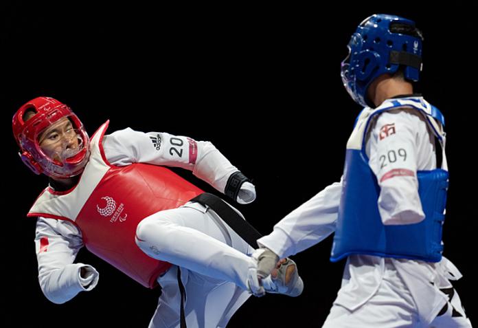 A male Para taekwondo athlete trying to kick his opponent's torso