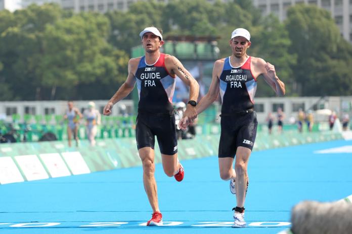 A male Para triathlete and his guide run side by side