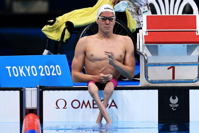 A male Para swimmer sits on the poolside