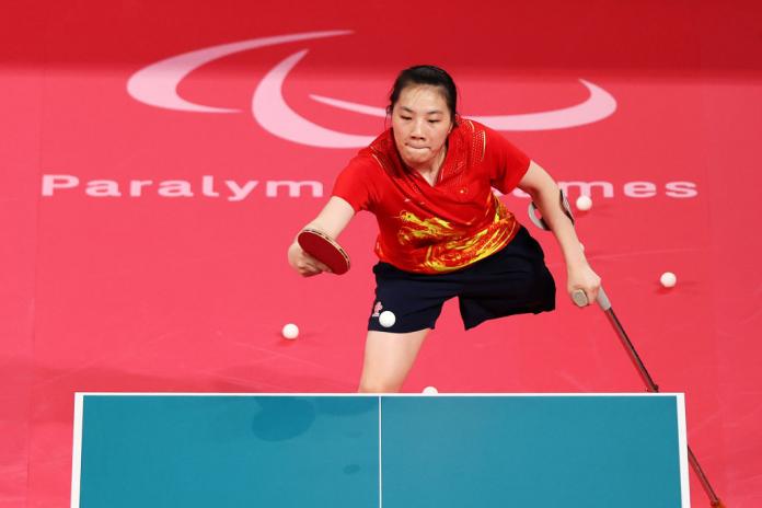 A female Para table tennis player competes using a cane
