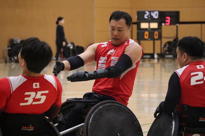 A male wheelchair rugby player speaks with his teammates during a training camp