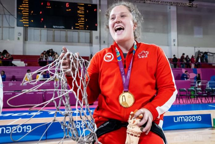 A female wheelchair basketball player poses for a photo after receiving a gold medal