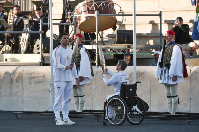 Beatrice Hess, left, hands her torch to pass the flame to Greece's Ioannis Fountoulis