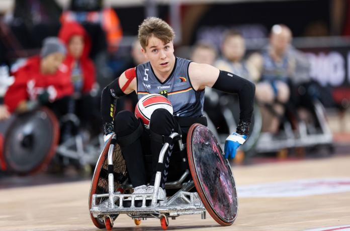 A male wheelchair rugby athlete carries the ball
