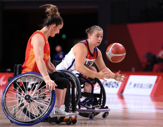 A female wheelchair basketball player bounces the ball during a game