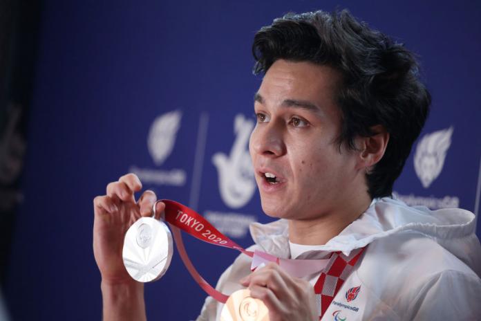 A male athlete shows his two medals from the Tokyo 2020 Paralympics.