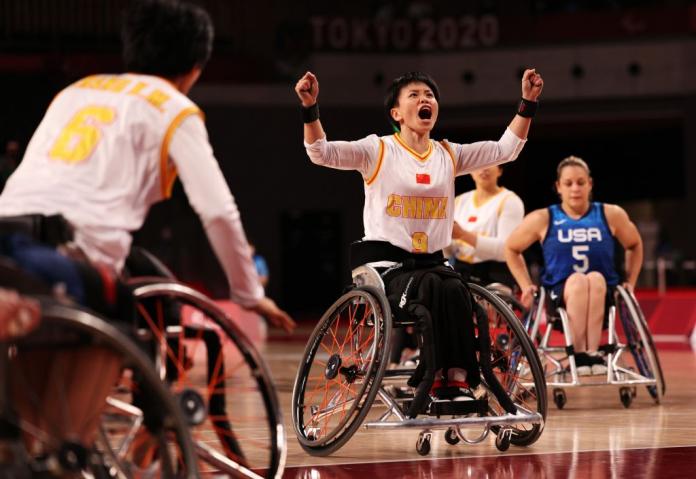 A female wheelchair basketball player pumps both fists