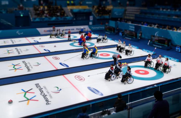 a wide shot of four wheelchair curling matches underway