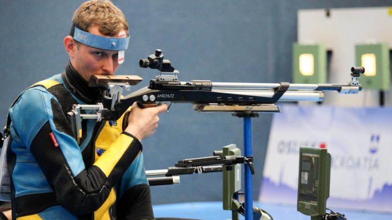 A man with a rifle in a sitting position at a shooting range