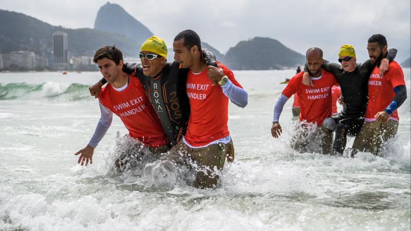 two male triathletes without legs being carried out of the sea in Rio