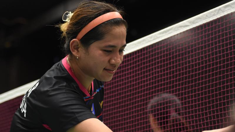 a female Para badminton player shakes hands with her opponent