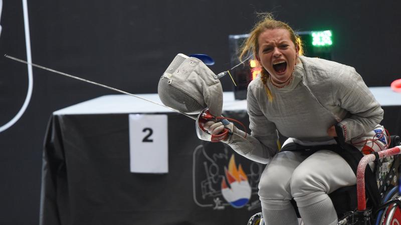 Female wheelchair fencer removes mask to celebrate
