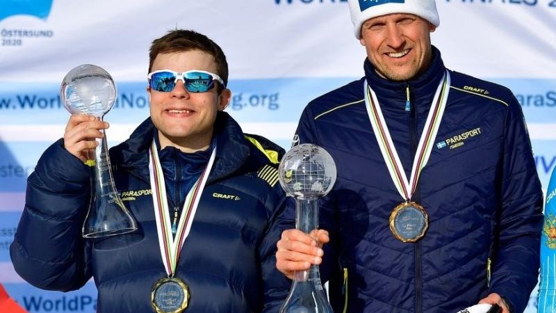 Two men holding with a medal showing their Crystal Globe trophy