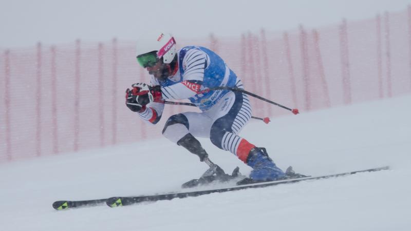 A men with a prosthetic leg skiing under heavy snow