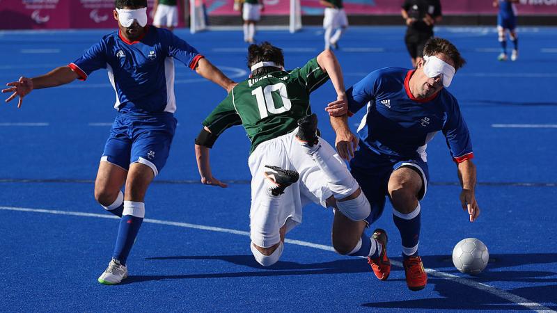 Two French defenders stop a Brazilian blind footballer