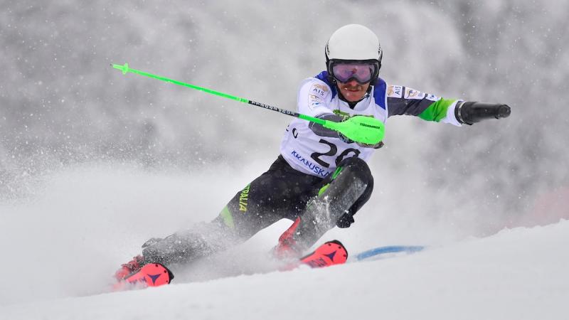 A man without an arm skiing in a Para alpine skiing competition