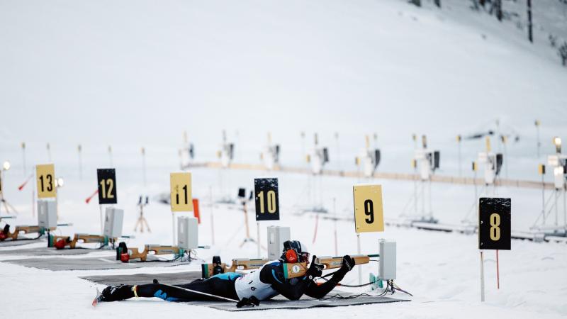 A man lying on the shooting range with a range and aiming.