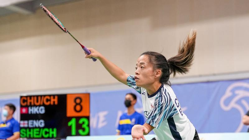 A female athlete plays badminton during a match.