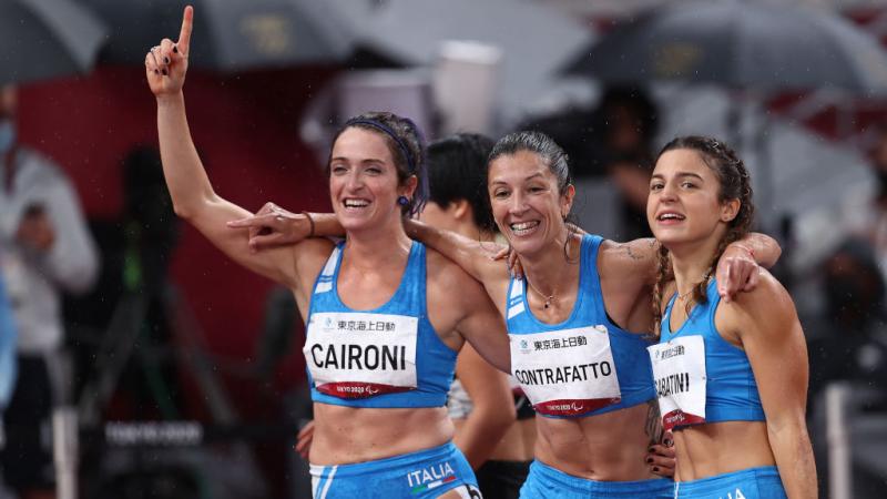 Three female Italian Para sprinters arm in arm and celebrating 