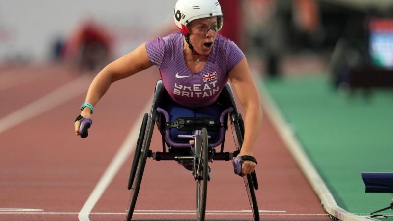 A female wheelchair racer crossing the finish line in an athletics track