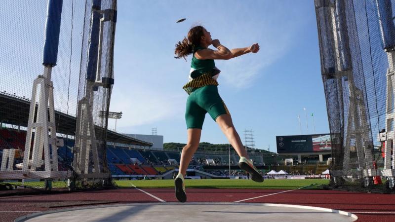 A female athlete throwing a discus in a stadium
