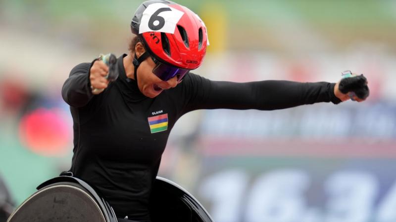 A female wheelchair racer open her arms to celebrate a victory