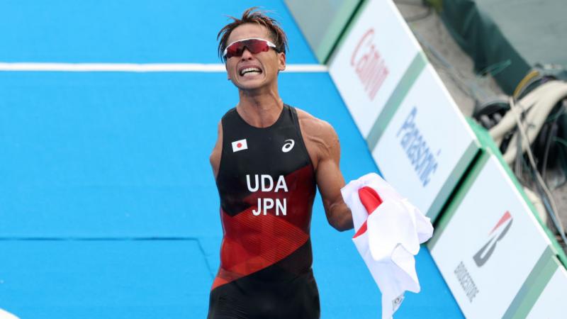 A male Para triathlon athlete reacts as he crosses the finishline