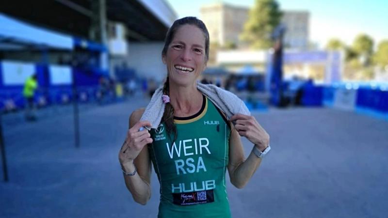 A female triathlete wearing South Afirca's green uniform smiles 