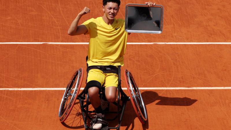 A male wheelchair tennis player poses for a photo after winning the 2024 French Open