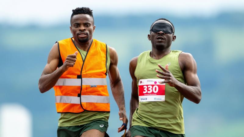 A male sprinter and his sighted guide competing