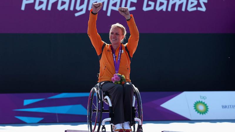 Esther Vergeer raises both hands to celebrate after receiving her gold medal.