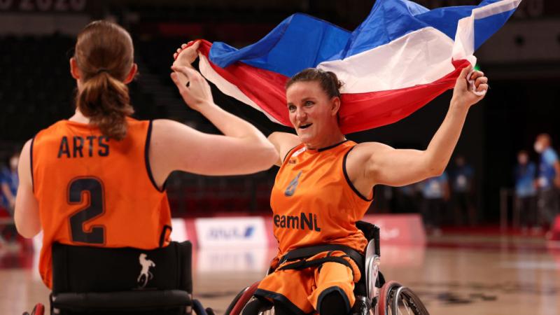 A female wheelchair basketball waves the Dutch flag to celebrate after a victory