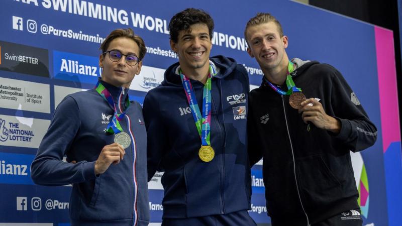 Three male swimmers showing their medals in a competition