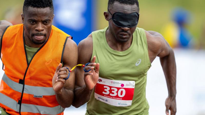A male sprinter and his sighted guide runner competing.