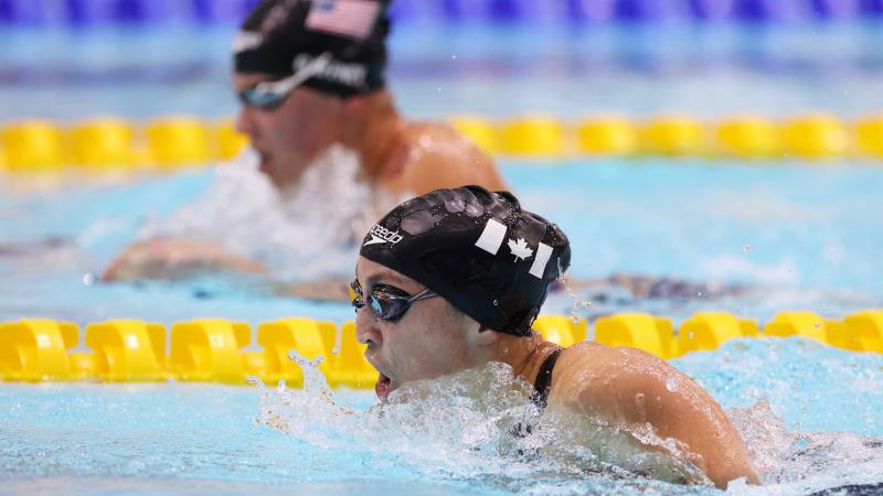 A female swimmer with another swimmer in the background in a race