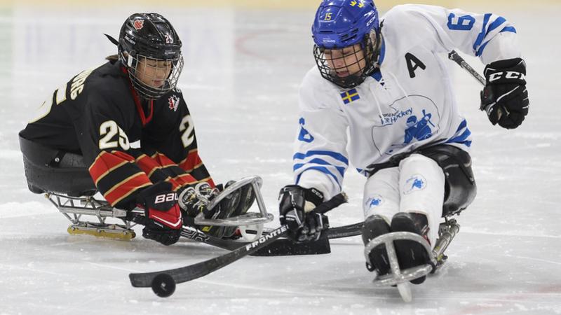 A Canadian player challenging a Team World player in a women's Para ice hockey game