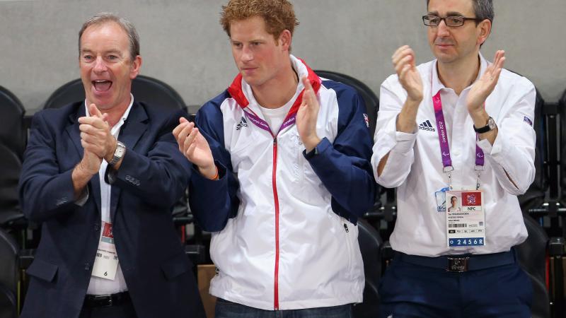 A picture of 3 men standing and applauding