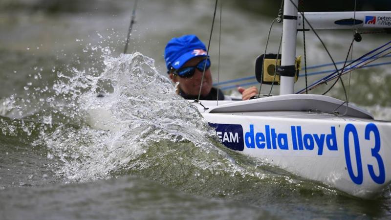 Water splashes up as a woman sails in a boat.