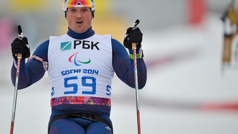 Close up of torso of sit skier driving forward through the snow with ski poles