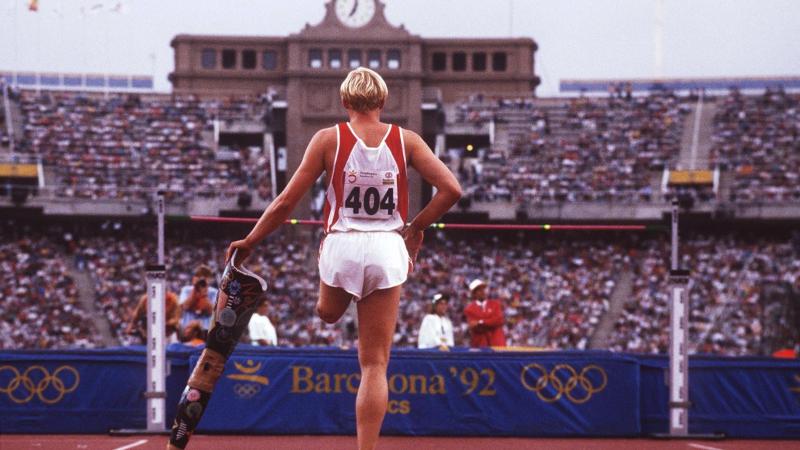 High jumper looking at the bar while holding a prosthetic leg in his hand.