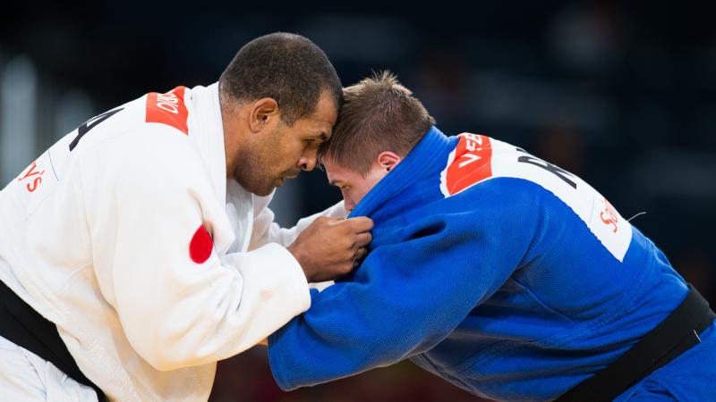 Antonio Tenorio and Vladimir Fedin hold on to each other with heads bowed close together, locked in battle