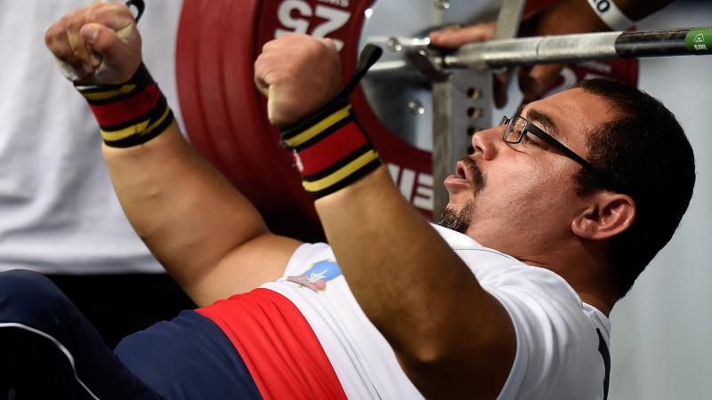 Chilean powerlifter Juan Carlos Garrido is on the bench and raises his hands celebrating his win.