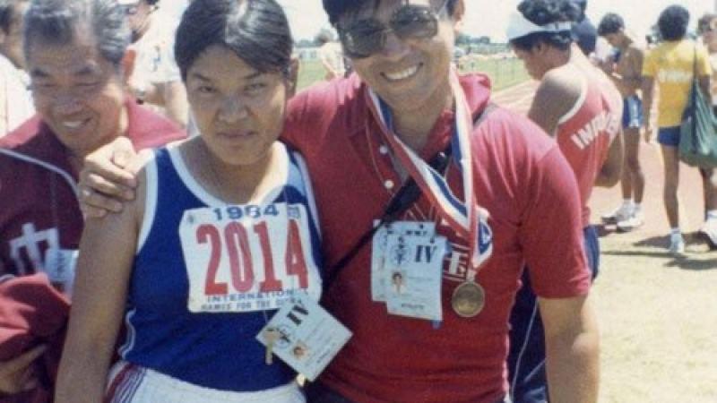 Two people posing for a photo in track clothes