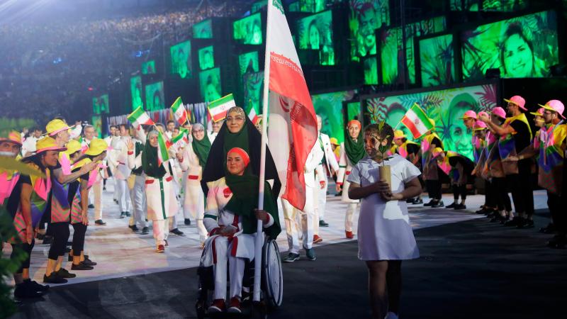 Woman in wheelchair carries Iranian flag during Opening Ceremony