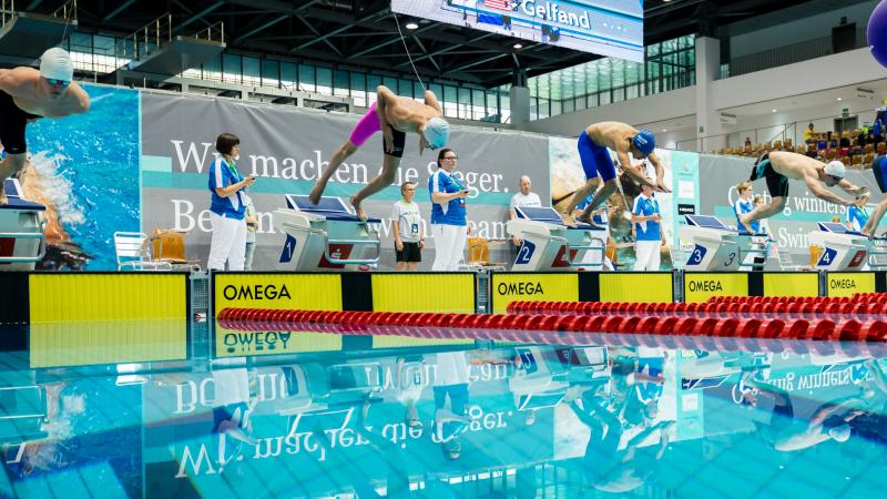 a group of men dive into a pool