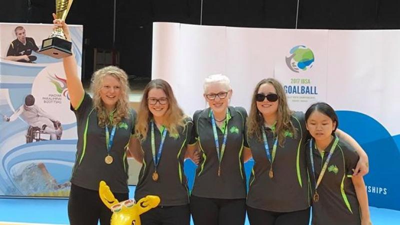 A group of female athletes celebrate with a trophy