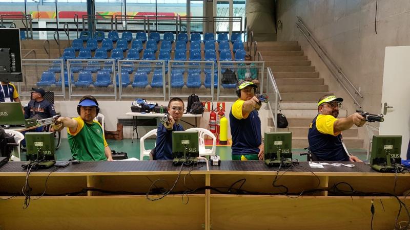 a row of male athletes compete with rifles in shooting Para sport