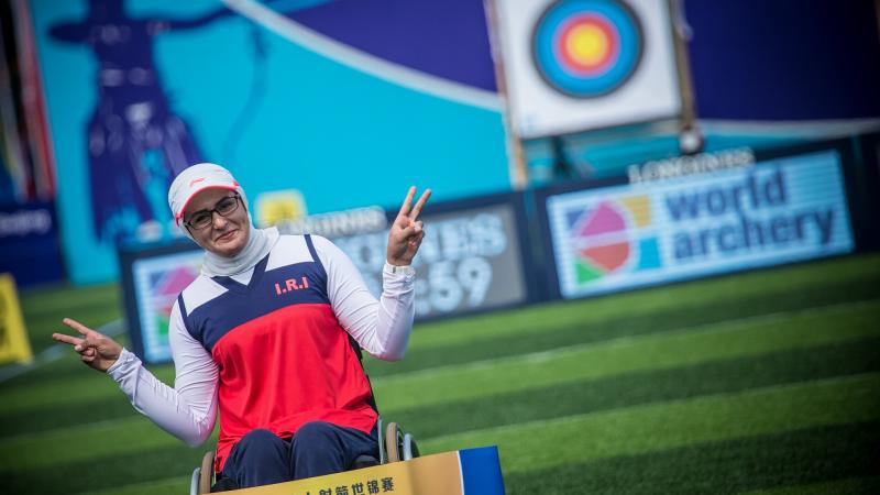 Female archer poses in front of a target